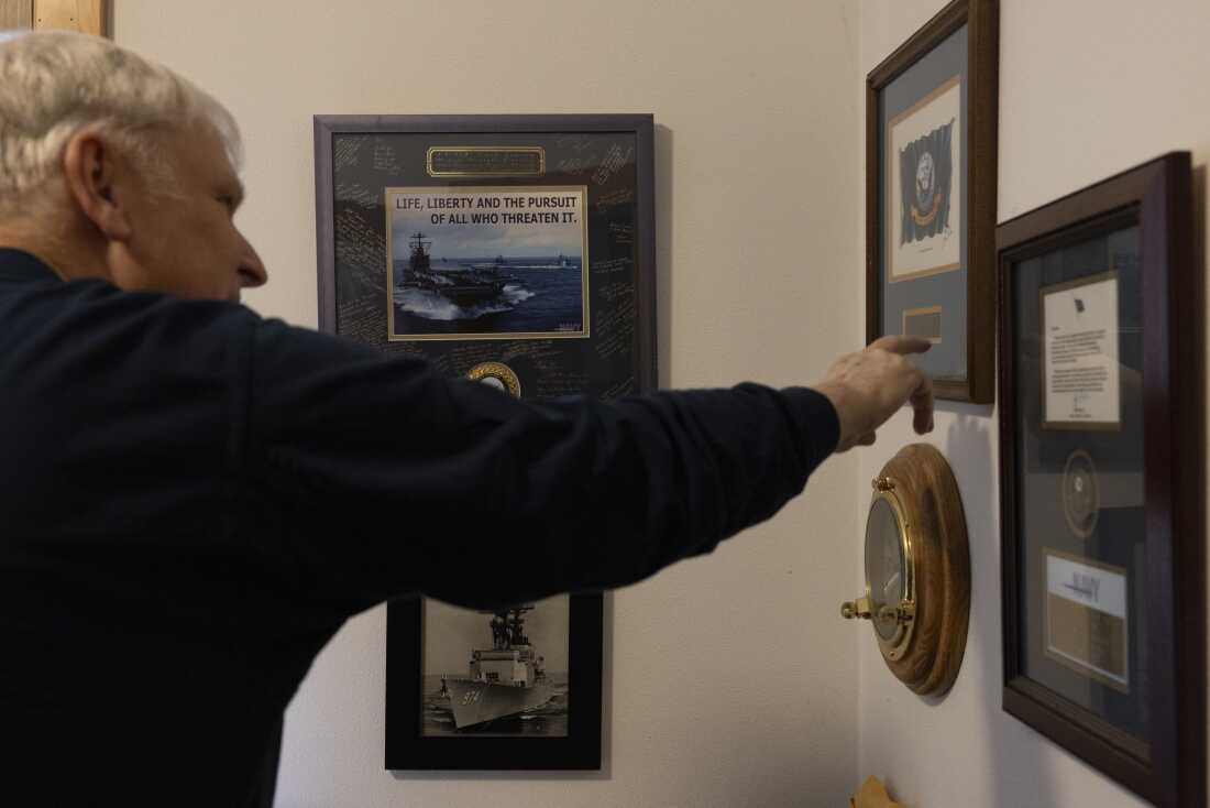 Erik Jensen points to Navy memorabilia and awards at his home. 