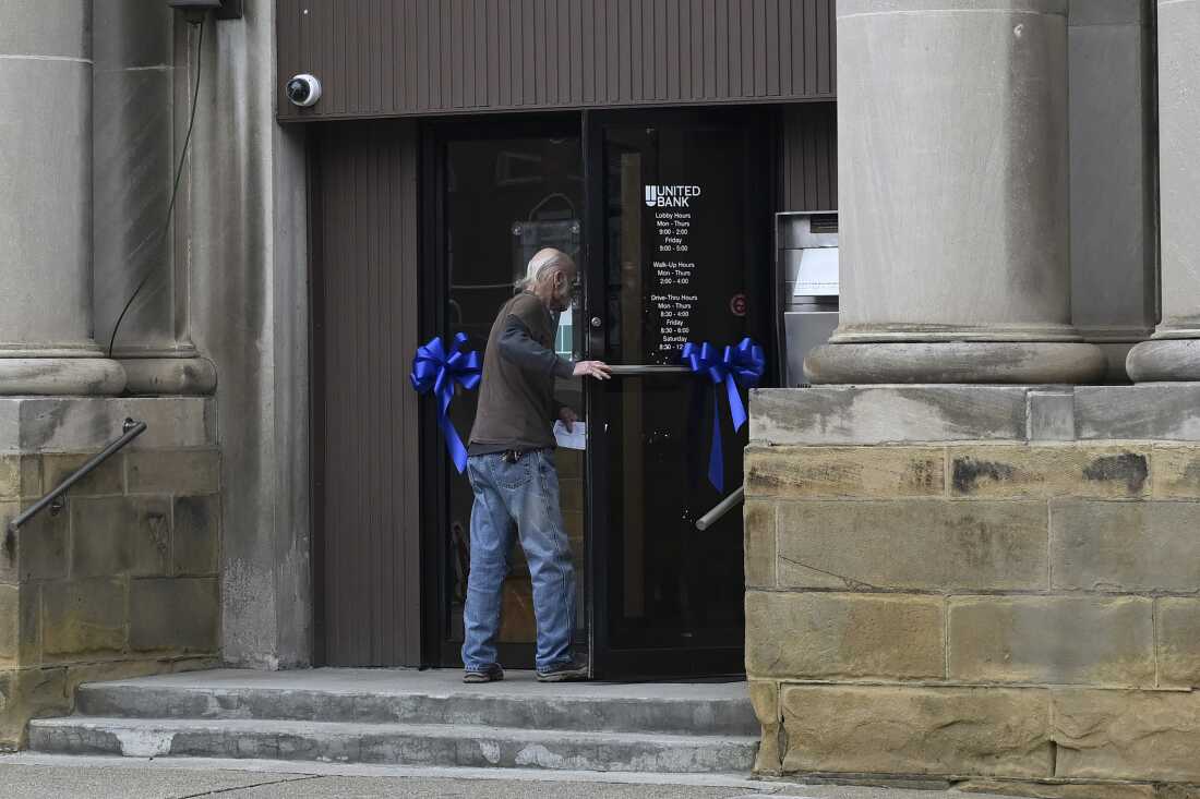 A pedestrian walks into United Bank as ribbons in honor of Sarah Beckstrom adorn the door on Main Street in Webster Springs, W.Va., on Wednesday.