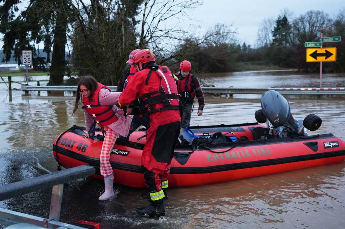 Maery Schine, 11, is helped out of a rescue boat by rescue workers with Chehalis Fire after evacuating with her father Patric, second from left, following flooding in Chehalis, Wash., on Tuesday.