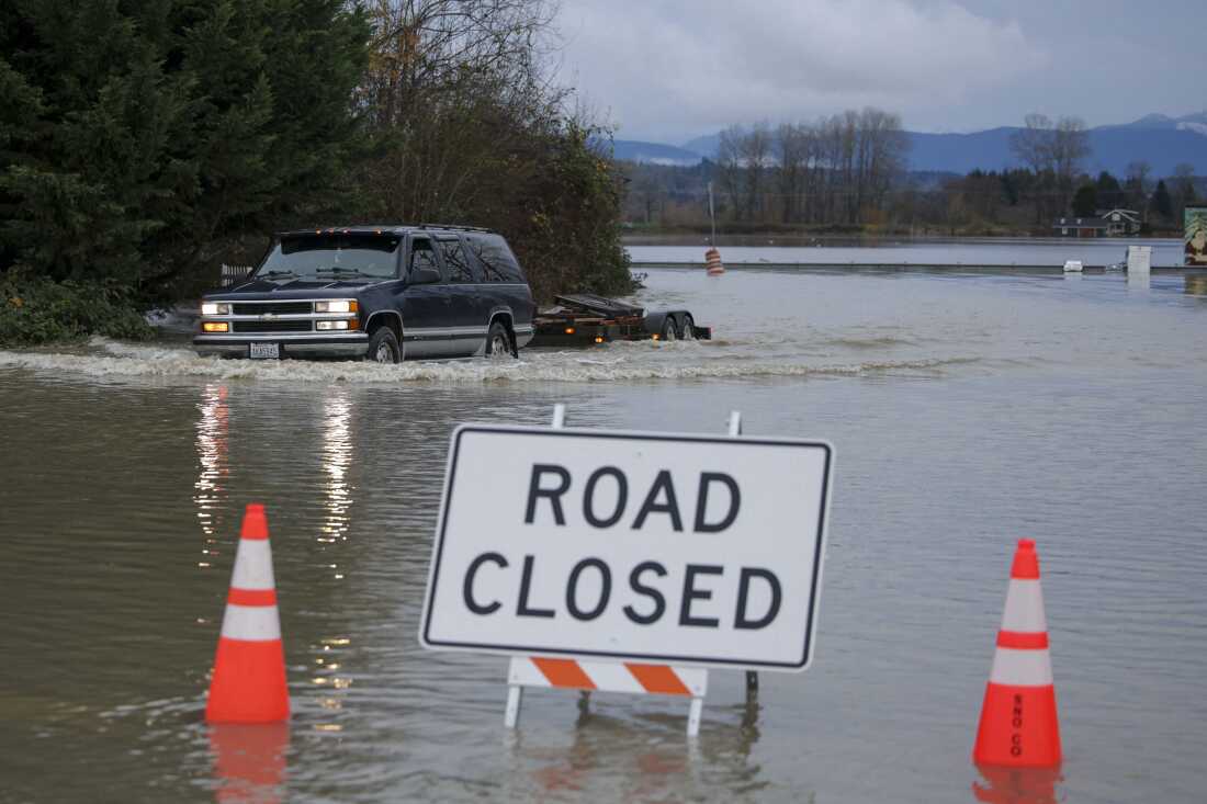 A person drives through flood waters from the Snohomish River in Snohomish, Wash., on Thursday. Tens of thousands of people were under evacuation orders Thursday in western North America, after days of heavy rain forced rivers to burst their banks.