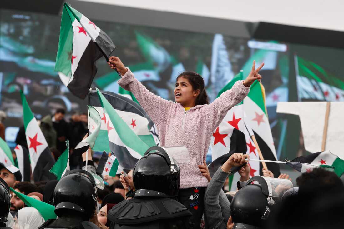 People wave the Syrian flag as they gather during celebrations marking the first anniversary of the ousting of former President Bashar al-Assad in Damascus, Syria, Monday.