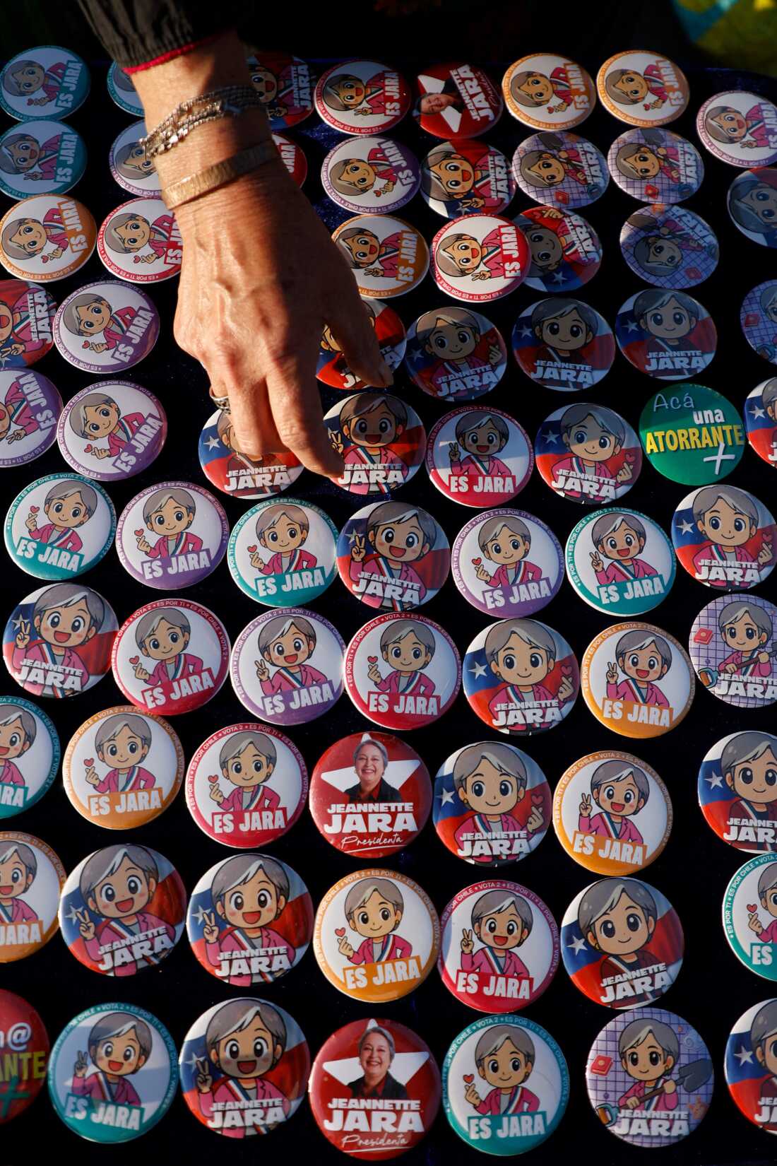 A person picks out lapel pins of Chile's presidential candidate Jeannette Jara, of the Unidad por Chile coalition, ahead of her closing campaign rally in Santiago on December 10, 2025.