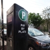 A cyclist rides past a Chicago Parking Meters LLC pay station in the 1100 block of West 18th Street in Chicago’s Pilsen neighborhood on May 15, 2025.
