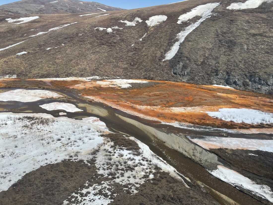 Iron, the result of thawing permafrost, creates orange water and snow in a braidplain of the Nakolikruk River, Alaska.