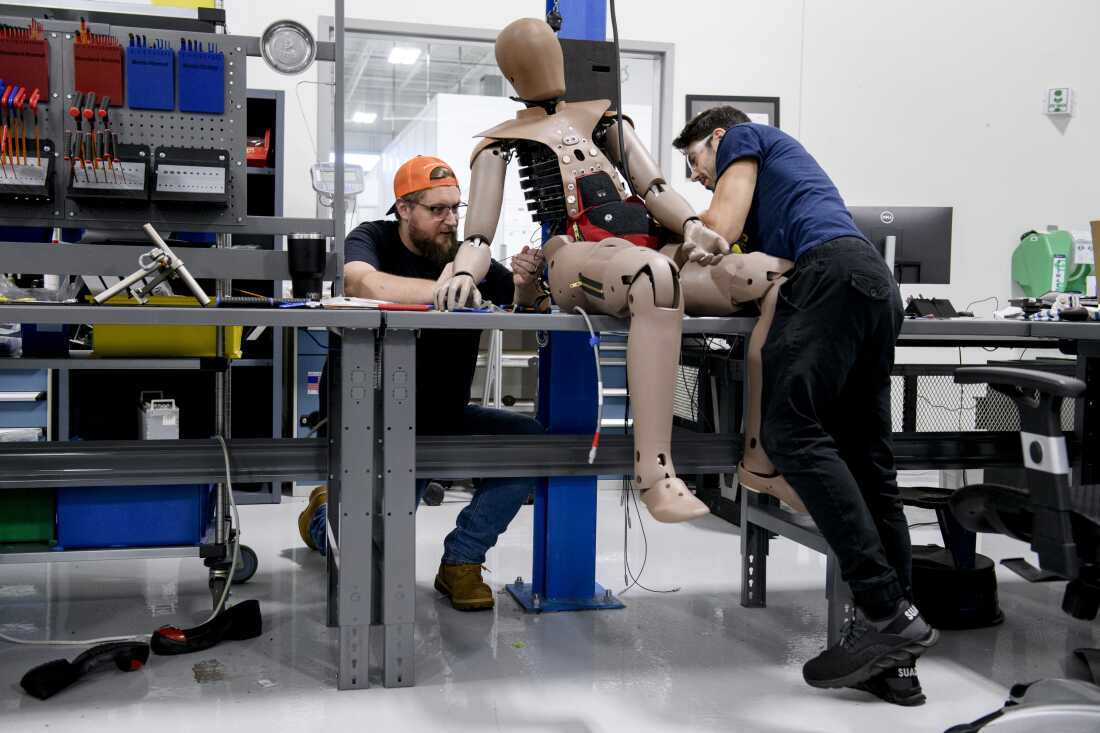 Lab Manager Robert Macdonald (left) and Evan Giangrande work to manage and neatly attach cables for a crash test dummy a Humanetics production facility in Farmington Hills, Mich.