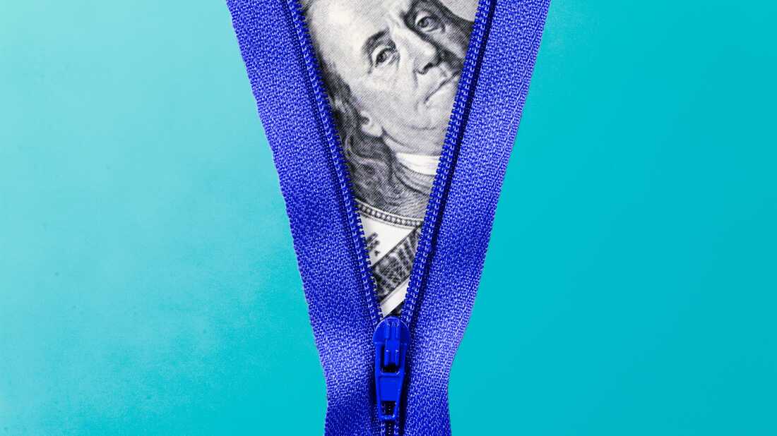 Close up photo collage of a dark blue zipper on a light blue backdrop, half-zipped, with a close-up of a 100 dollar bill peeking through behind the zipper.