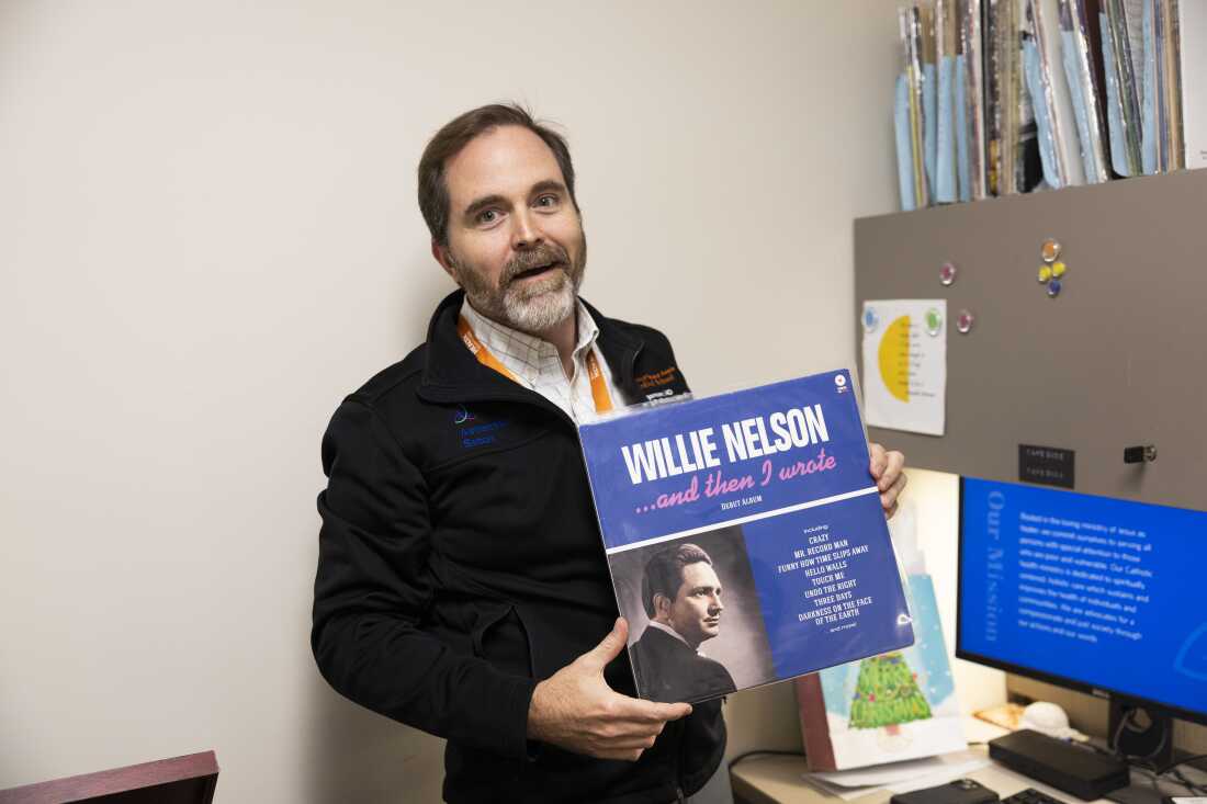 Dr. Tyler Jorgensen, a palliative care doctor at Dell Seton Medical Center, holds a Willie Nelson album in an office on December 9, 2025. Ferguson said patients have been increasingly requesting country music and they had to source that genre specifically.