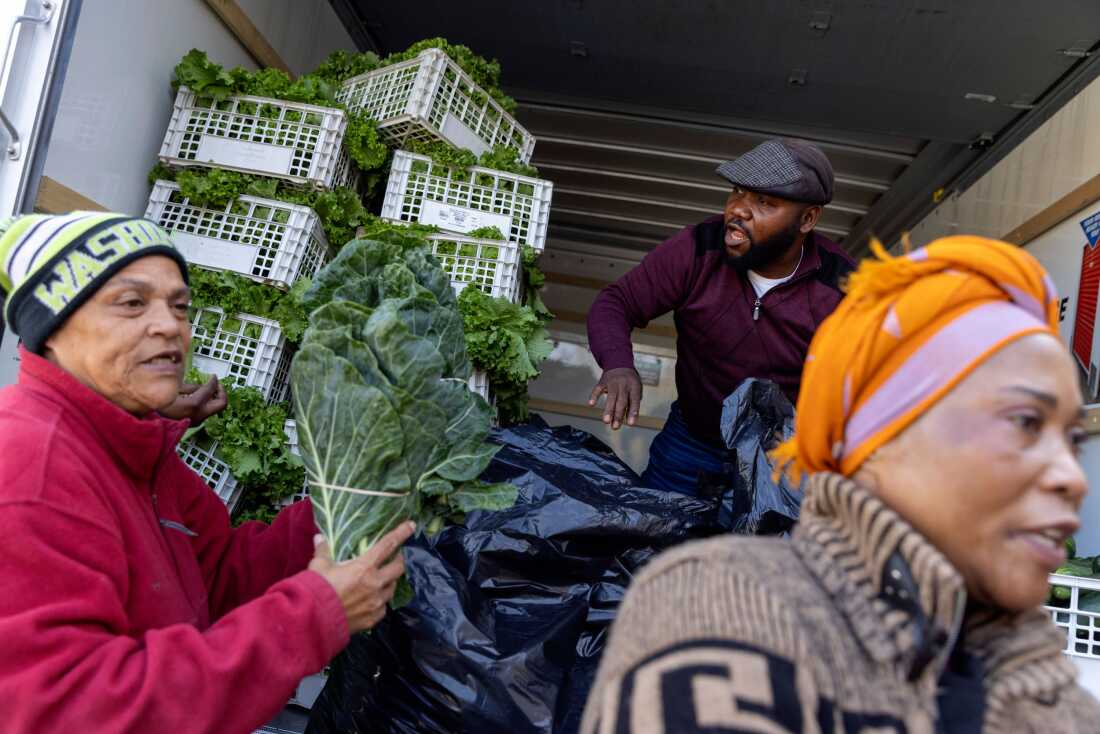 Agnes Mwamba, right, and her husband, Joseph, middle, of Agnes Farm and Produce in Brandywine, Md. offload 2000 pounds of fresh vegetables that they brought for a food distribution for federal workers in Hyattsville, Md. On the left is Grace Herring, a volunteer with No Limit Outreach Ministries, where the distribution was taking place, on Oct. 28, 2025.