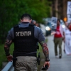 A corrections officer walks beside people holding candles, signs, and flowers during a vigil outside the Krome Detention Center in Miami in May 2025, protesting U.S. Immigration and Customs Enforcement custody and mass deportations.