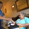 Lidia Vilorio gives her patient Martina Negron her medicine and a snack in her home.