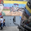 People walk past a mural depicting former Venezuelan president Hugo Chavez alongside Venezuelan independence heroes in Caracas on Dec.17, 2025. 