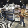 A See's Candy worker restocks the display next to a cutout of Warren Buffett at the Berkshire Hathaway shareholders meeting exhibit hall Friday, May 2, 2025 in Omaha, Neb. (AP Photo/Josh Funk)