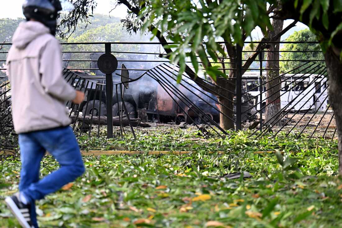 A person walks near a burnt missile interceptor vehicle at La Carlota air base in Caracas on Saturday.