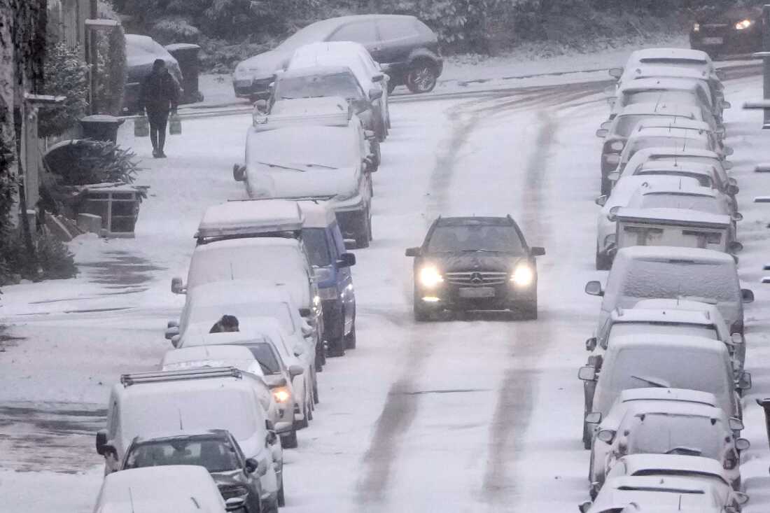 A car drives carefully on a snowy street when people facing a cold wave bringing winter weather with snow and ice to the industrial Ruhr area in Gelsenkirchen, Germany, Wednesday, Jan. 7, 2026. 