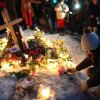 A person places a candle at a makeshift memorial for 37-year-old Renee Good, who was shot by an Immigration and Customs Enforcement agent on Wednesday in Minneapolis. The outdoor memorial has flowers, candles and a wooden cross embedded in the snow.