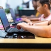 A stock photo shows elementary school students working on laptops.