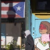 A pedestrian walks past the flag of Puerto Rico and the colorful door to the sanctuary apartment of Chicago's Adalberto Memorial United Methodist Church in Chicago in 2021. The church has provided shelter to immigrants in the U.S. illegally.