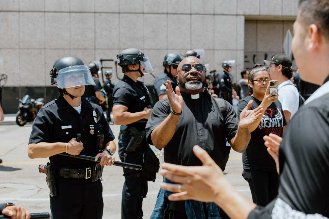 A priest claps as protesters conitnue anti-ICE demonstrations in Los Angeles, California, on June 9, 2025.