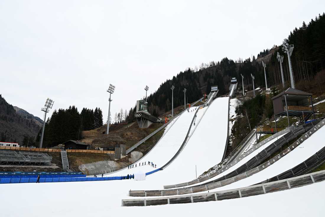 A view of the Predazzo Ski Jumping Stadium during the Italian Championships Open ski jumping event, held in Predazzo in December. The venue has multiple steep slopes covered in snow.
