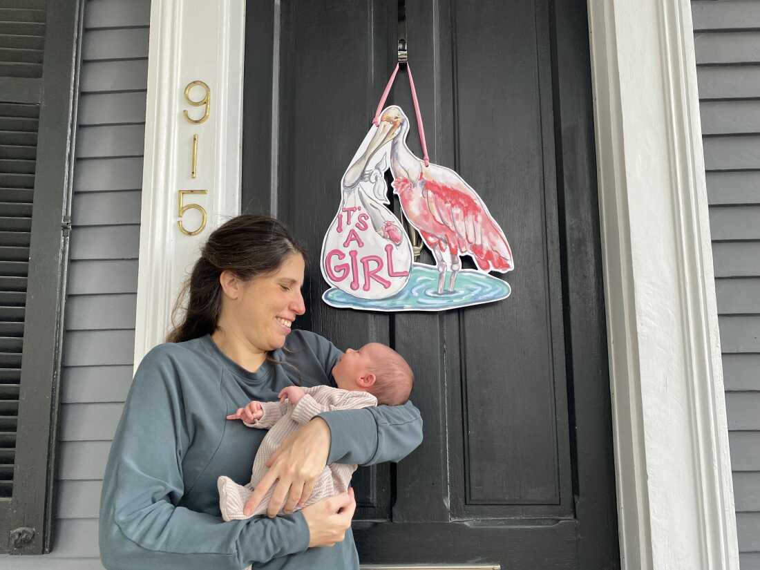 Lisa Bonfield shows her new daughter Adele the sign welcoming her home on the porch of their home in New Orleans on Dec. 12, 2025.