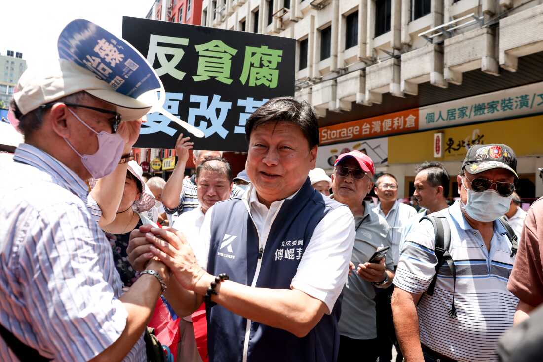 Leader of the Kuomintang (KMT) caucus at the Legislative Yuan Fu Kun-chi (C) shakes hands with supporters outside of the Legislative Yuan 
