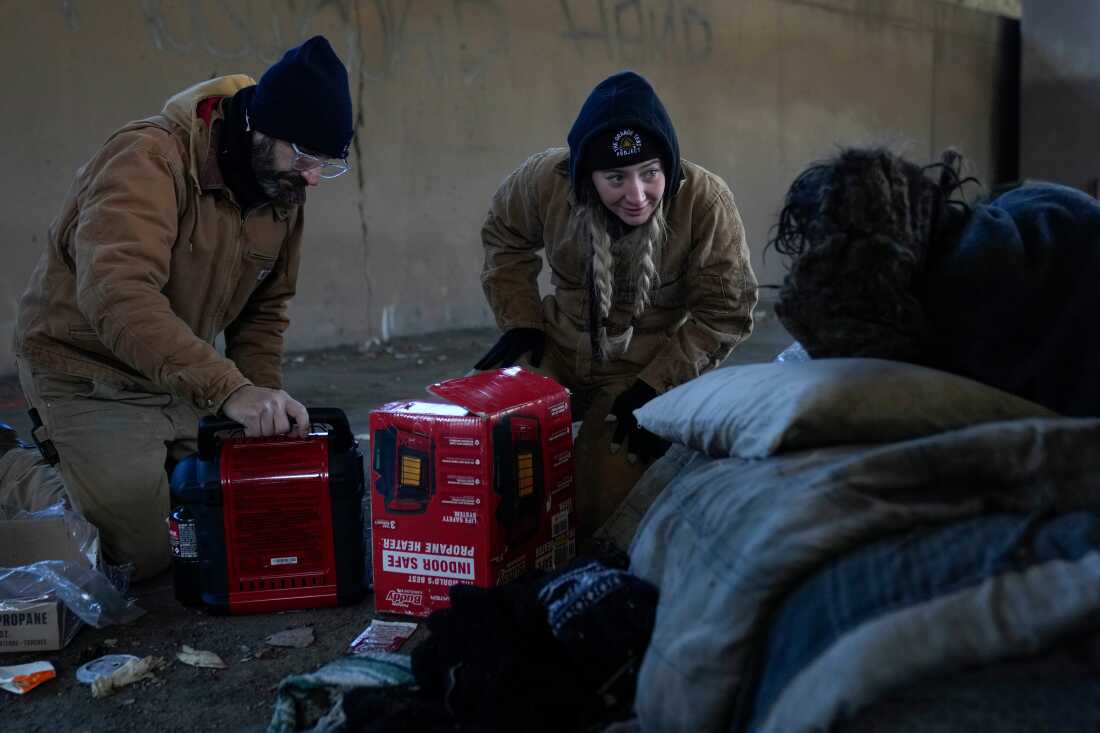 Jim Matthess, left, and Morgan McLuckie with the Orange Tent Project nonprofit set up a propane heater for an unhoused individual during dangerously cold temperatures Friday, Jan. 23, 2026, in Chicago. 