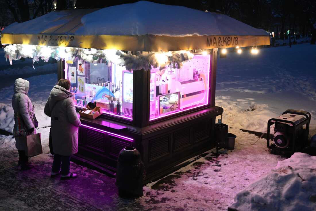 Customers stand at a coffee booth supplied with power generator electricity during a scheduled power outage