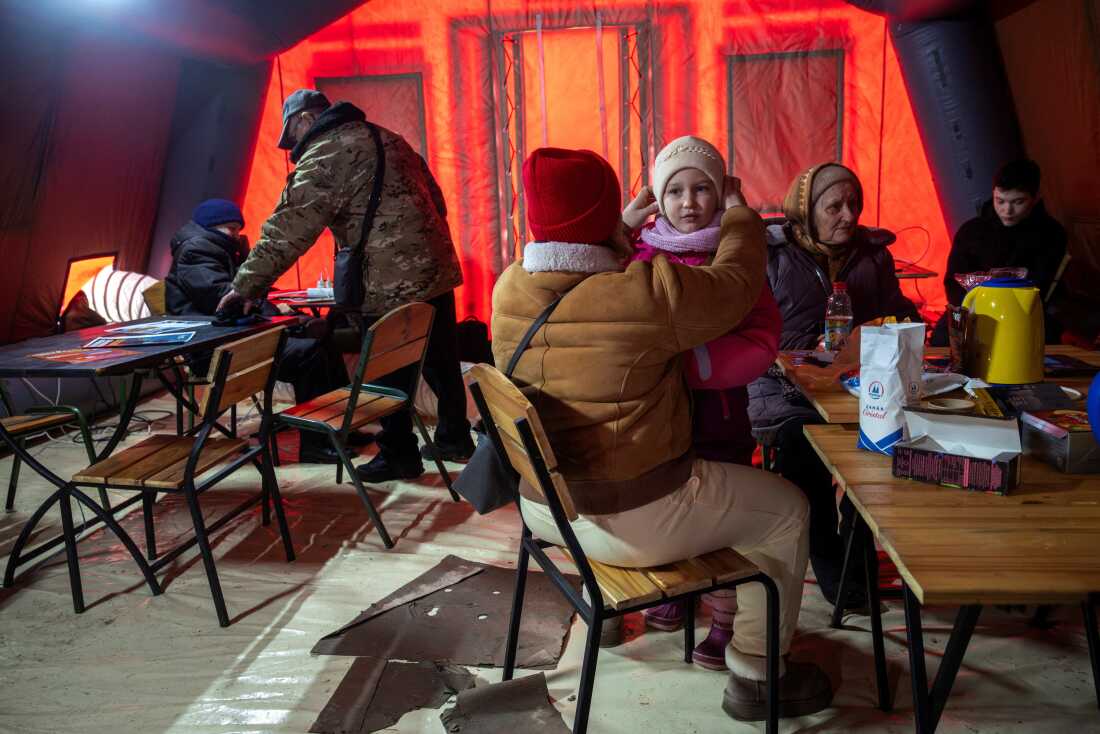 People warm up in a tent provided by emergency services 