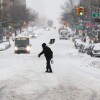 A man carries a shovel as he crosses a street in the Hamilton Heights neighborhood in New York on Sunday.
