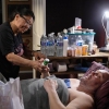 Irma Nunez gives her client Thomas Draa a drink at his bedside. She has been caring for him for 12 years.