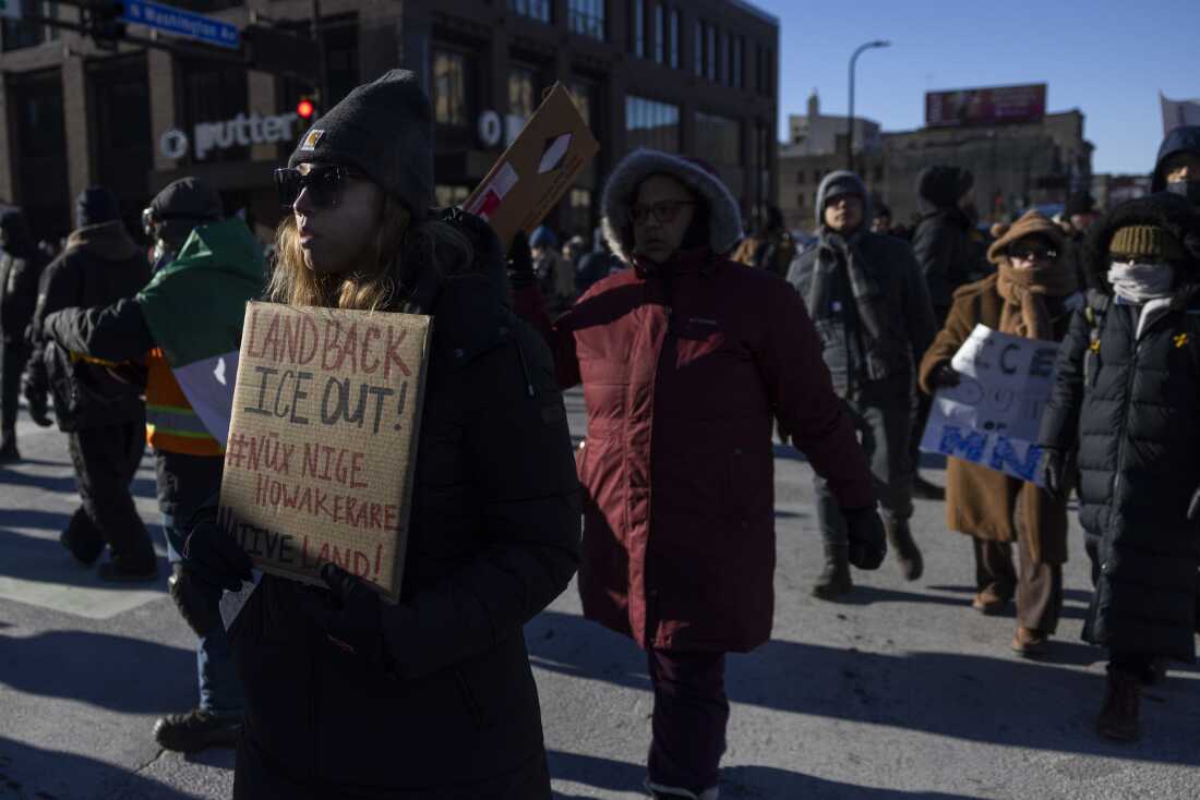 A demonstrator holds a sign that reads "Land Back, ICE Out!" during a protest in downtown Minneapolis on Friday calling for an end to Operation Metro Surge.