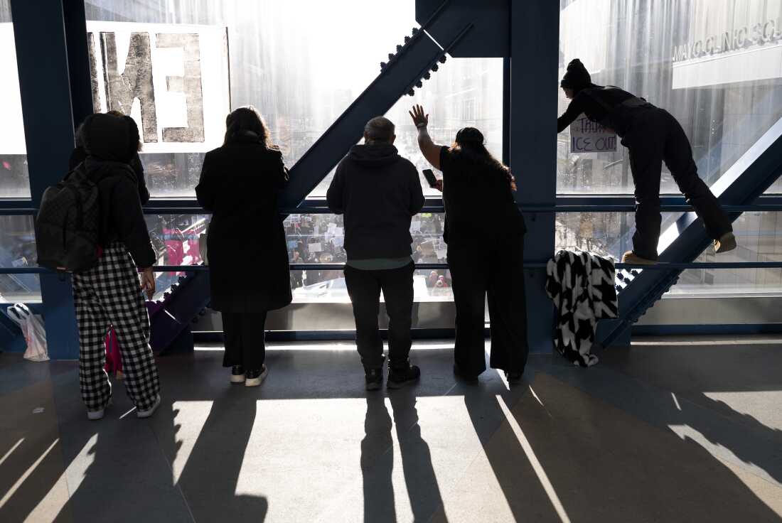 ]People look on from a skyway as demonstrators march during a "Nationwide Shutdown" demonstration against ICE enforcement on Friday in Minneapolis. Protests continue calling for an end to immigration raids in the Twin Cities which have already resulted in the deaths of Alex Pretti, a 37-year-old ICU nurse at a VA medical center who died January 24, after being shot multiple times during a brief altercation with border patrol agents, and Renee Good a 37-year-old mother of three children who was killed by ICE agents on January 7th.