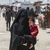 A woman carries a child as she walks through the al-Hol refugee camp in northeastern Syria in October 2023.