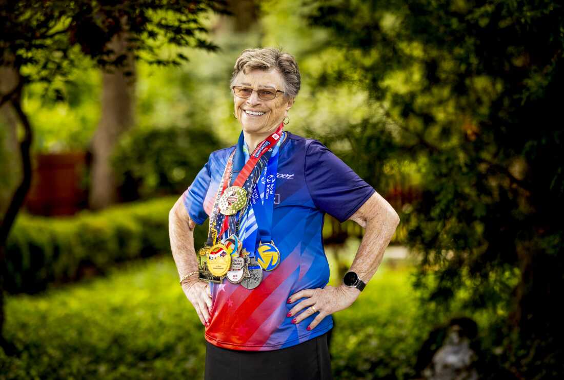 Luise Easton poses with some of her triathlon medals at her home. Despite issues with her heart, she's still planning to keep up with her training.