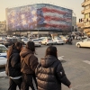 People walk in front a billboard with graphic showing a U.S aircraft carrier with damaged fighter jets on its deck, and sign reading in Farsi and English: "If you sow the wind, you'll reap whirlwind," at the Enqelab-e-Eslami (Islamic Revolution) square, in Tehran, Iran, Sunday, Jan. 25, 2026.