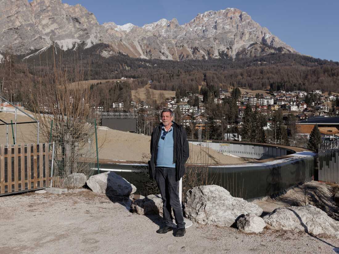 Luigi Casanova, director of the local environmental group Mountain Wilderness, stands before the construction site of the new bobsleigh track for the Milano Cortina 2026 Winter Olympics. Casanova and other activists have criticized the project for the destruction of ancient larch forests and the broader environmental impact on the UNESCO World Heritage site, labeling the urbanization of the Alpine landscape as a "betrayal" of the Games' sustainability pledges